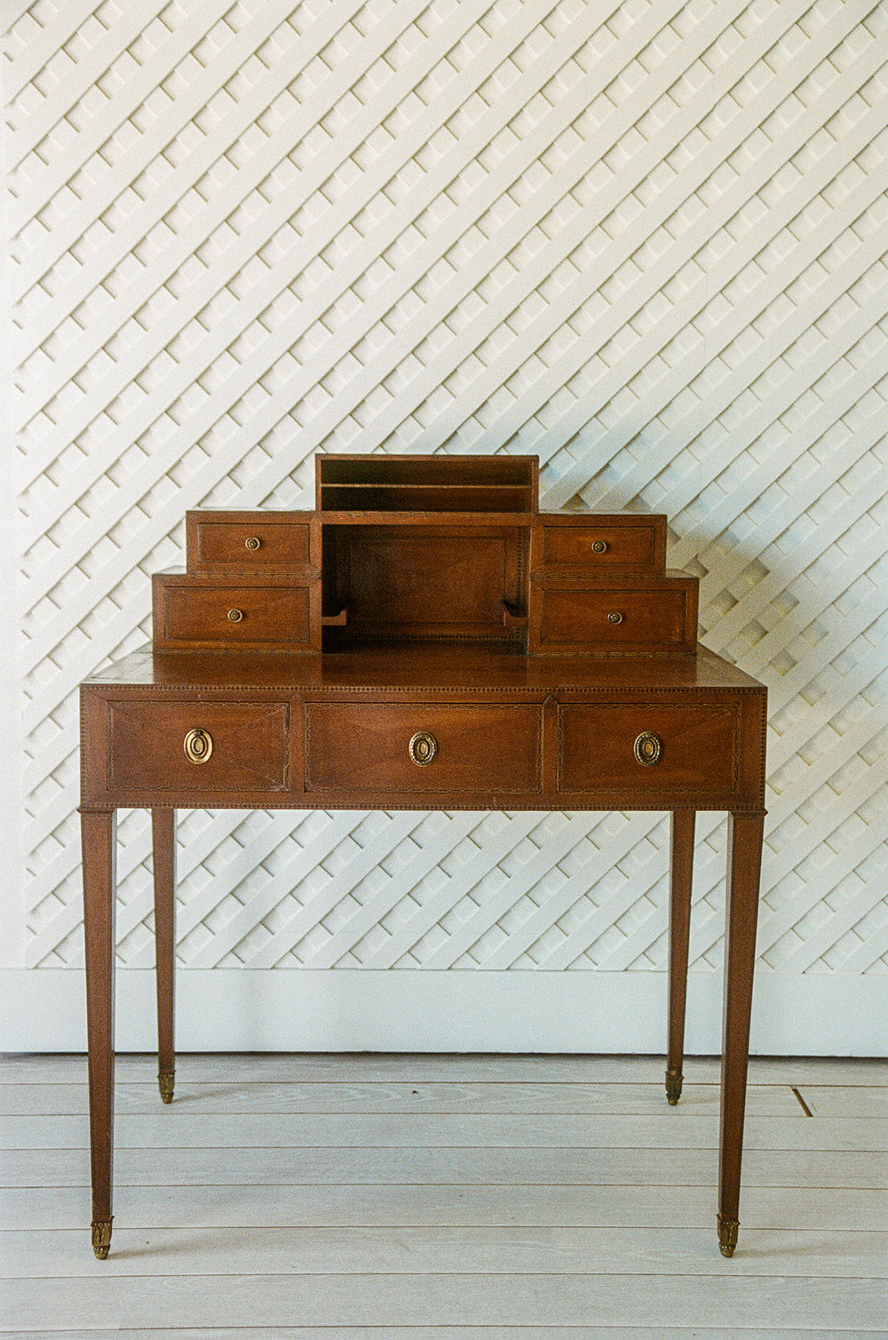 Antique writing desk from the front, a stepped bank of small drawers and an open compartment above three inlaid drawers, on tapered legs with brass caps