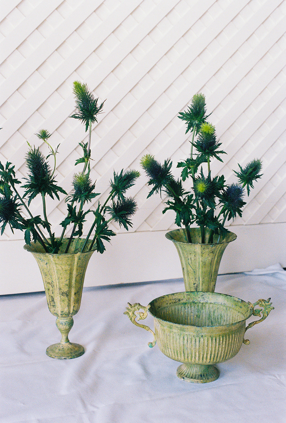 Three pale green tole planters, a footed urn between two trumpet vases