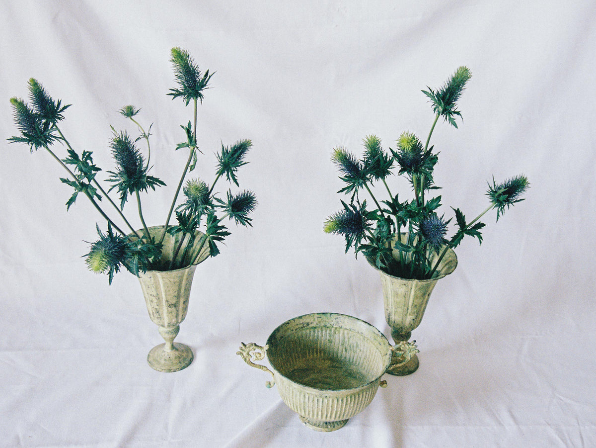 Three pale green tole planters, a footed urn between two trumpet vases, seen from above