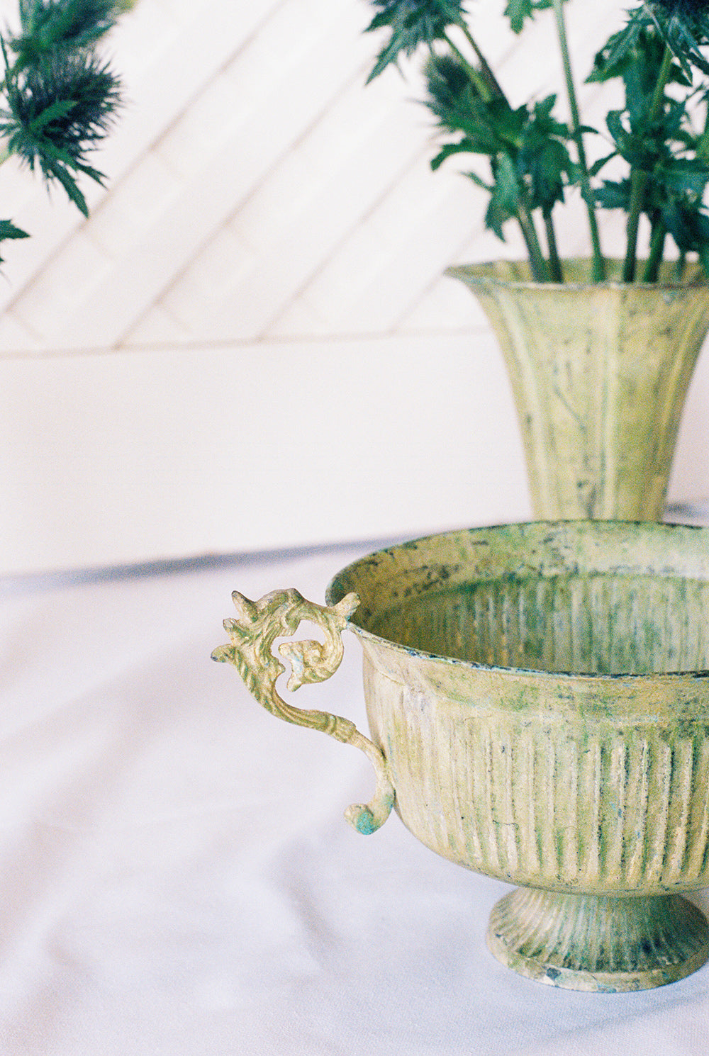 Three pale green tole planters, a footed urn between two trumpet vases, close view