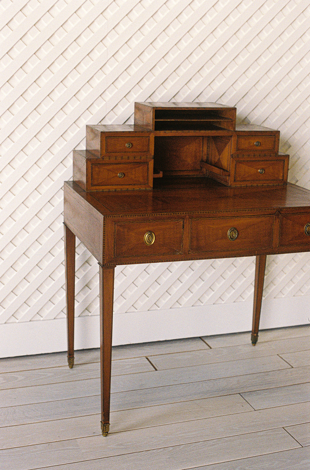 Antique writing desk with inlaid borders, stepped drawers and tapered legs, from the side