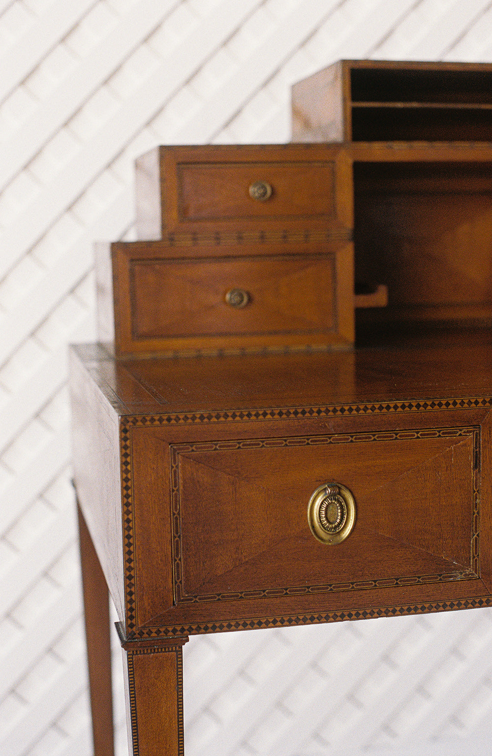 Antique writing desk with inlaid borders, stepped drawers and tapered legs, from the side