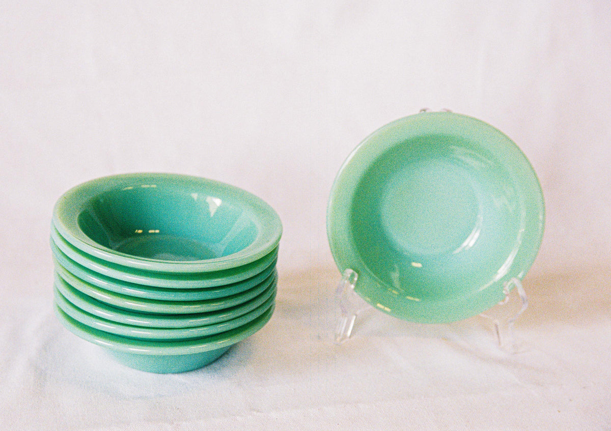 Eight jadeite glass soup bowls, stacked, with one upright