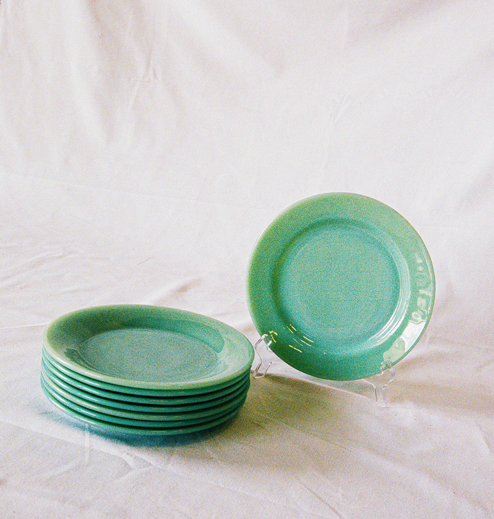 Eight jadeite glass salad plates, stacked, with one upright