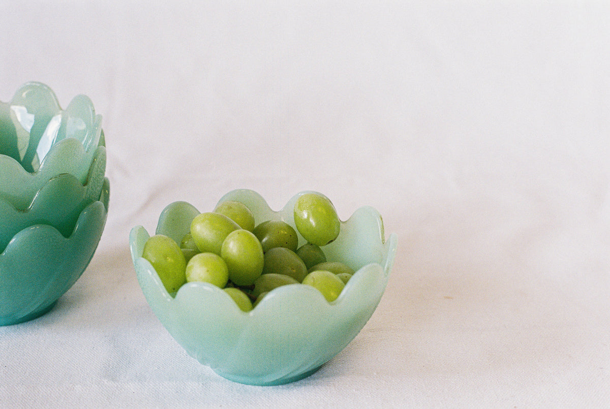 Jadeite glass bowls with scalloped rims, holding grapes