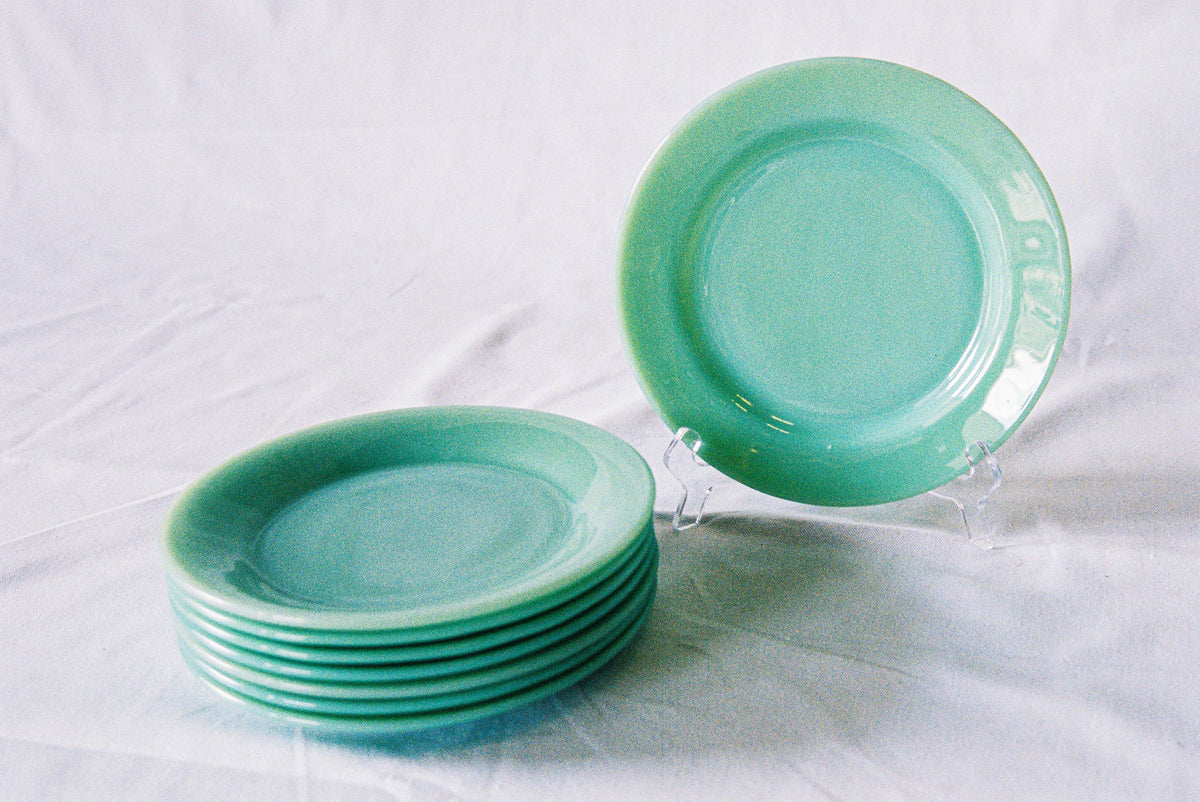 Eight jadeite glass dinner plates, stacked, with one upright
