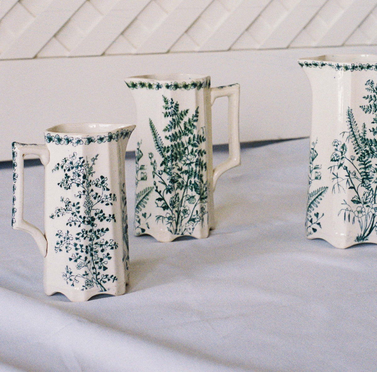 Three Victorian botanical transferware pitchers, close view