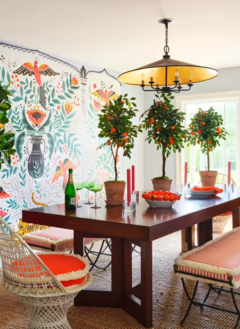 Dining room with a painted bird and floral mural, potted orange trees and a dark wood table