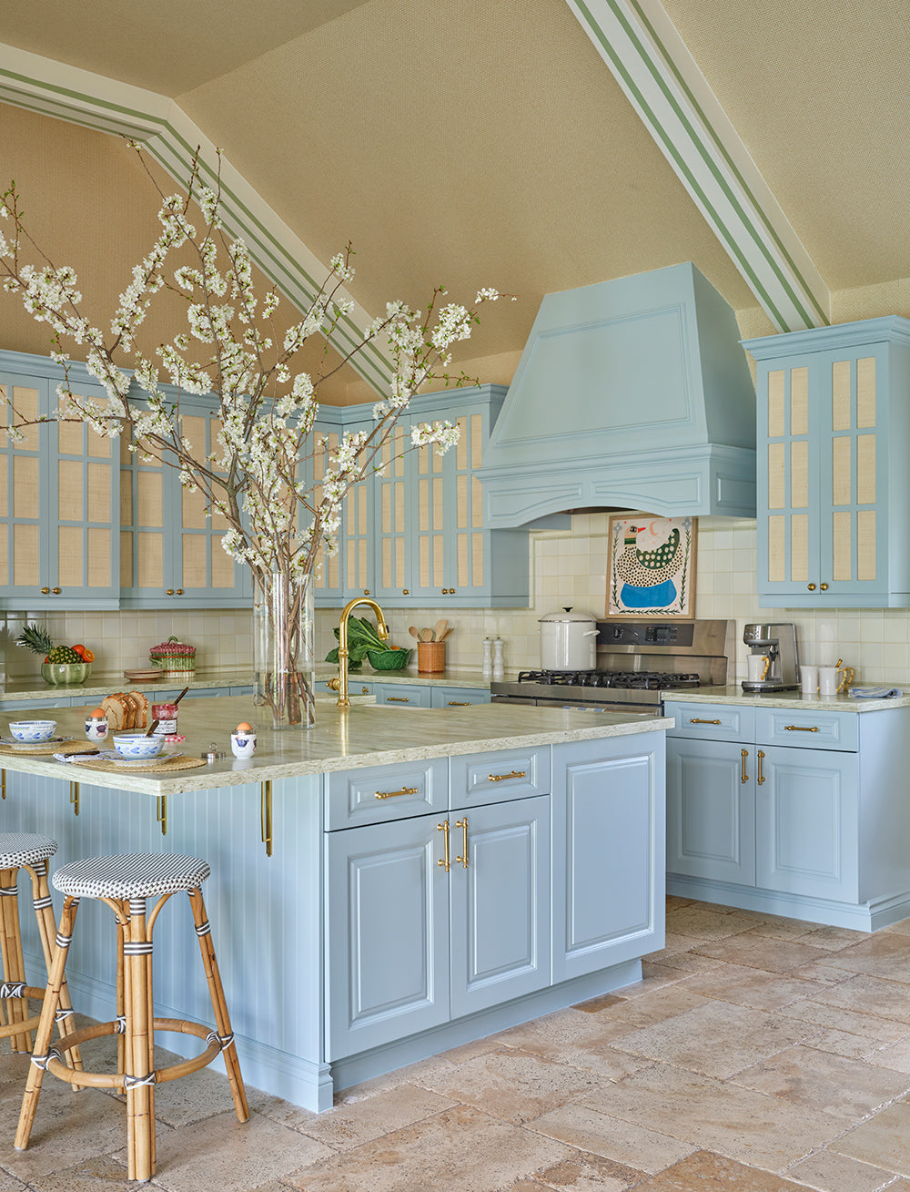 Kitchen with light blue cabinetry, a range hood and an island with rattan stools