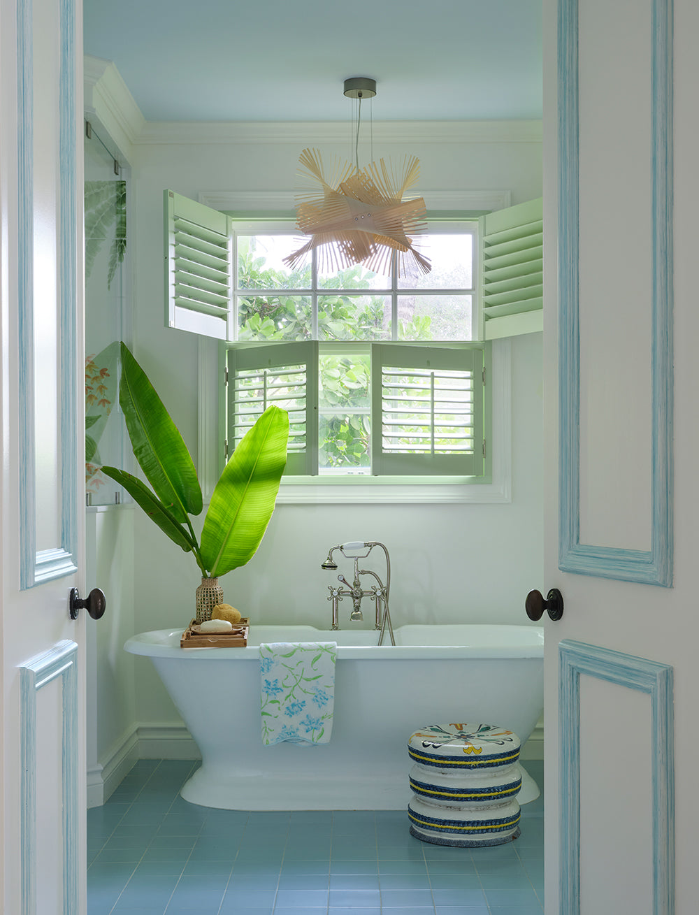 Bathroom with a clawfoot tub, pale blue trim and a shuttered window