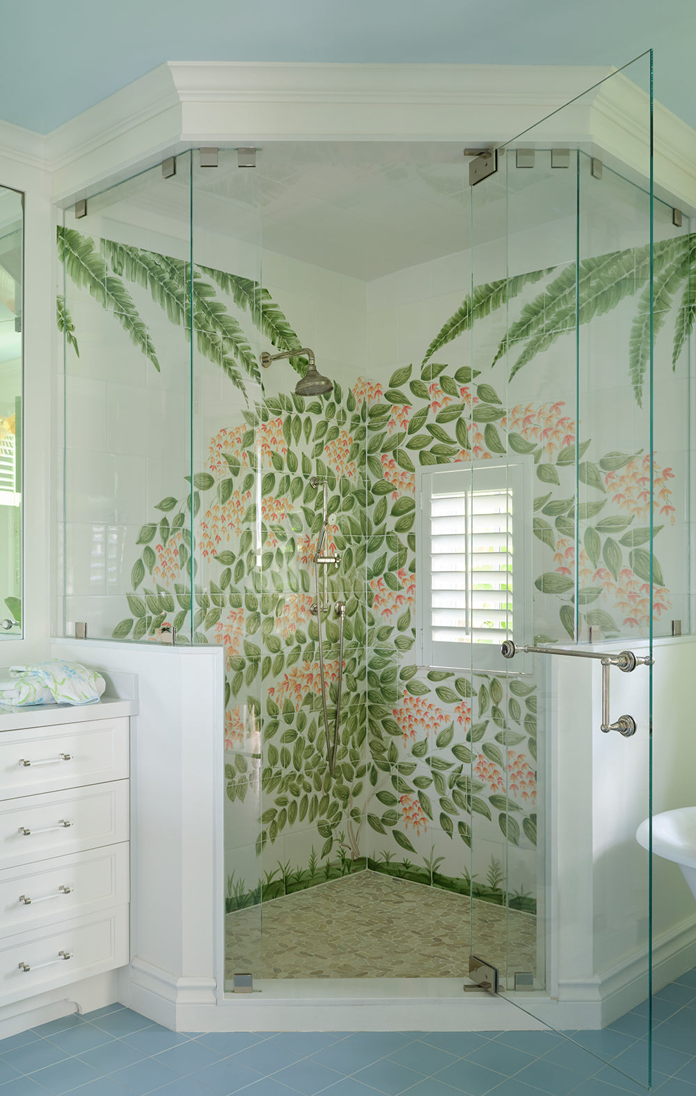 Shower with a painted tropical leaf mural and glass doors