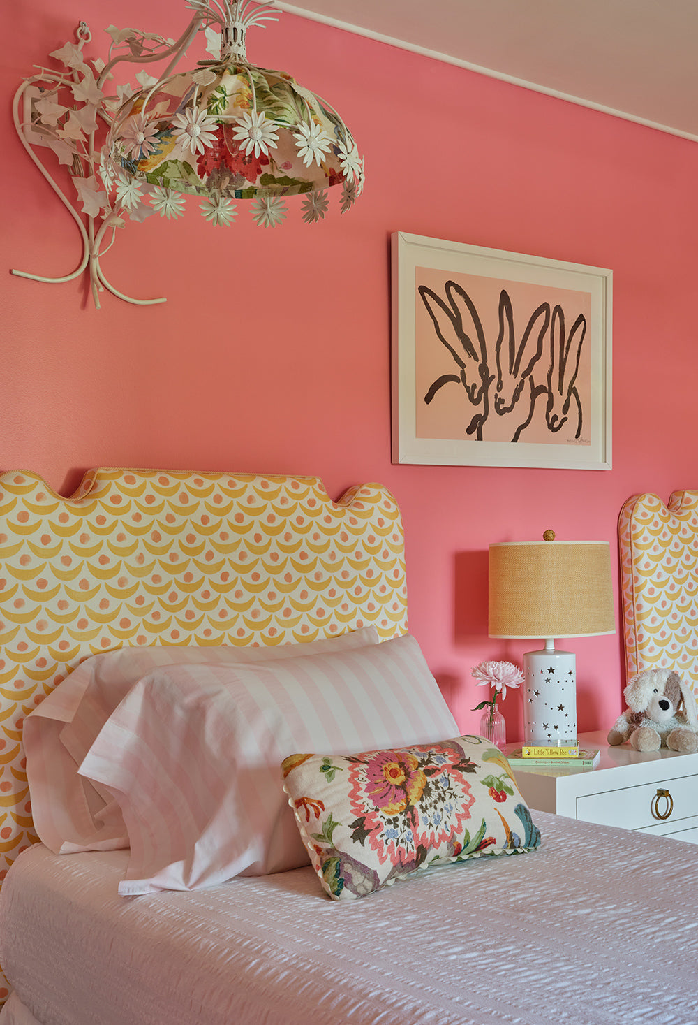 Coral pink bedroom with a yellow patterned headboard and a framed print