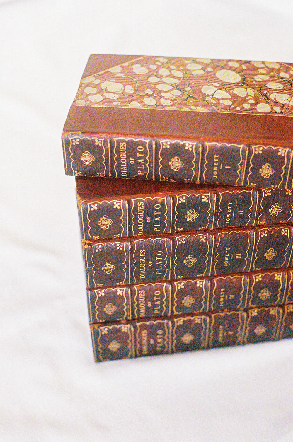 Five leather bound volumes of the Dialogues of Plato, translated by Jowett, with gilt tooled spines, seen from above
