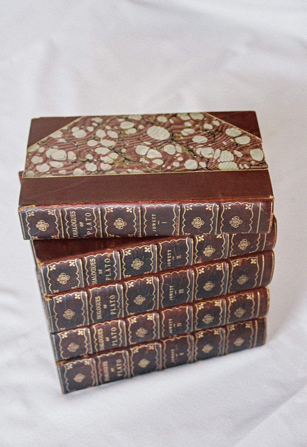Five leather bound volumes of the Dialogues of Plato, translated by Jowett, with gilt tooled spines, seen from above