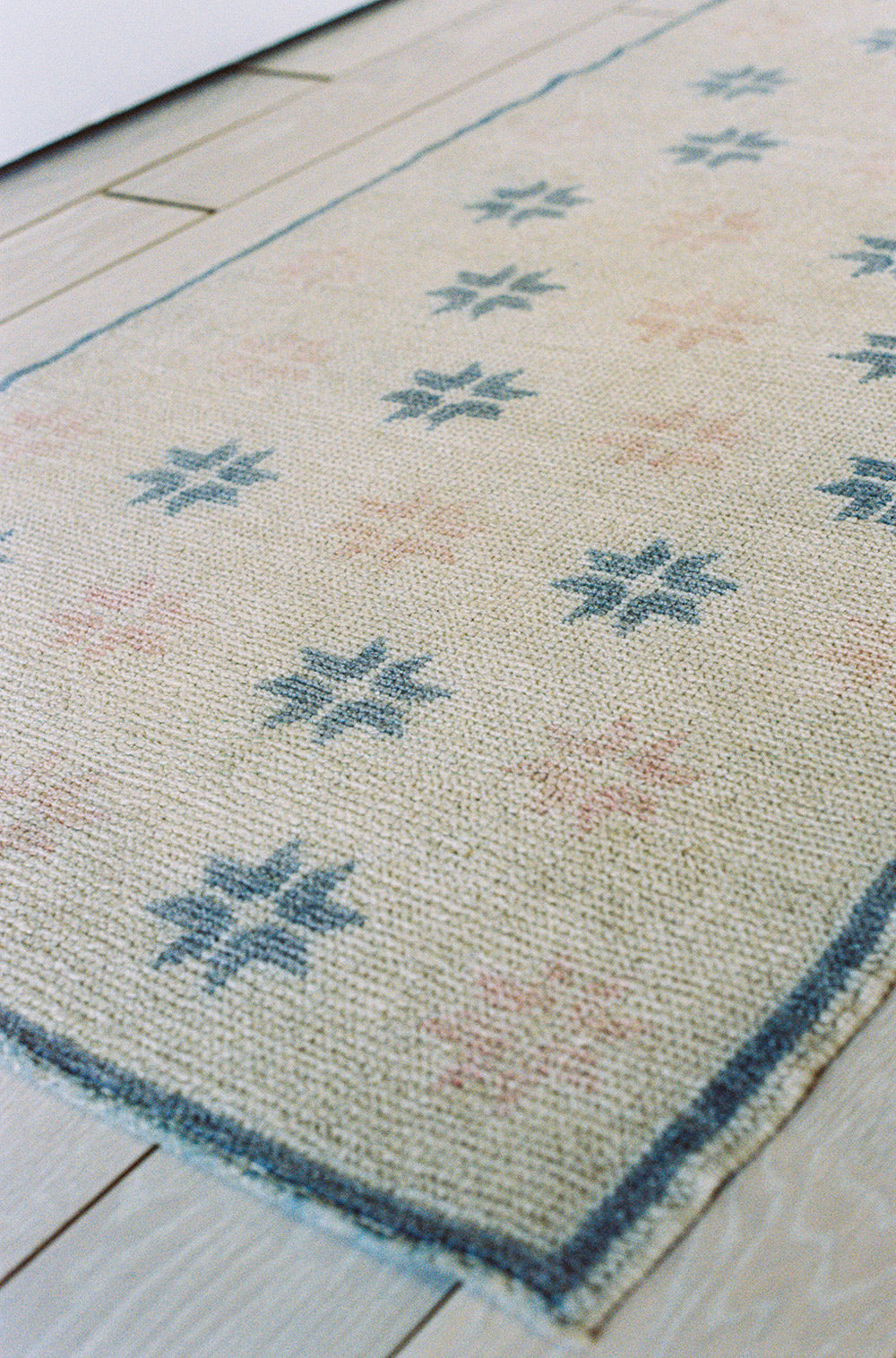 Wool runner with a starburst pattern in white, pink and blue, from the side
