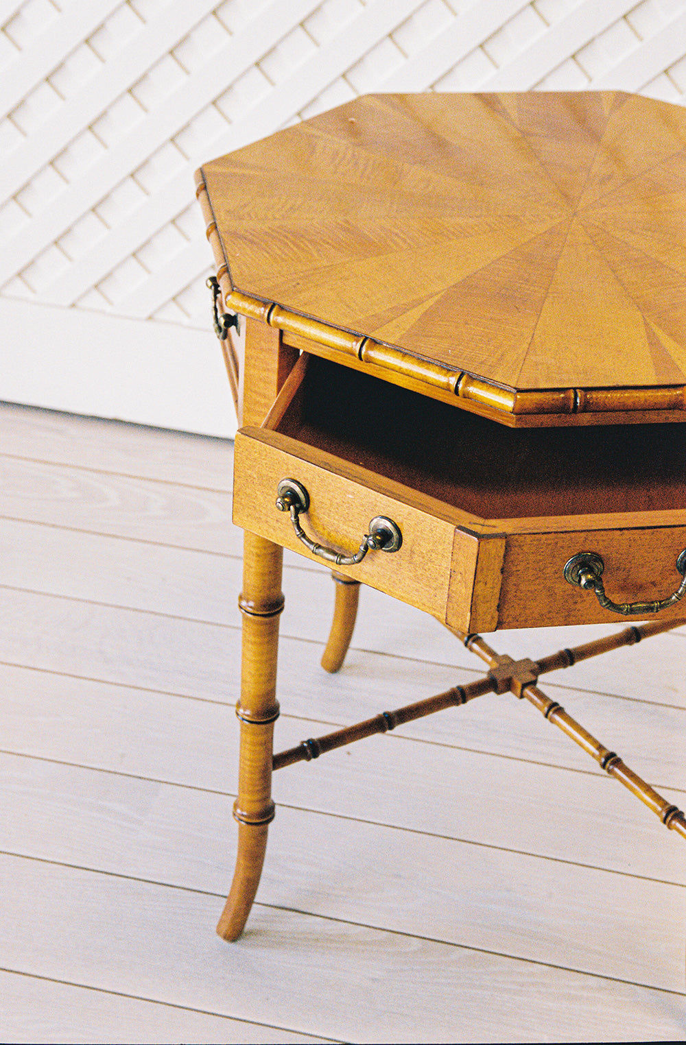 Octagonal bamboo end table with one drawer and a starburst veneer top, from the side