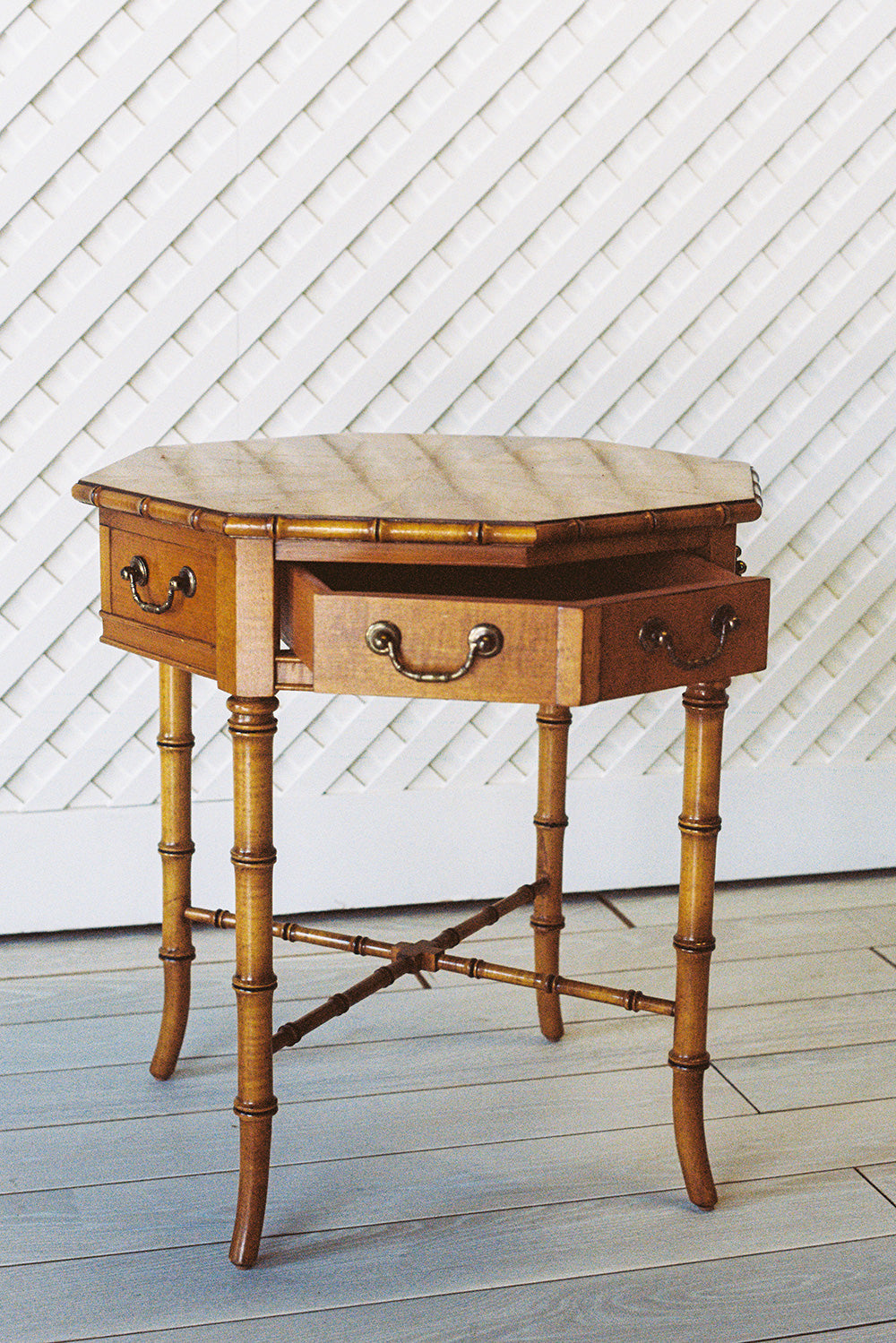 Octagonal bamboo end table with one drawer and a starburst veneer top, from the side