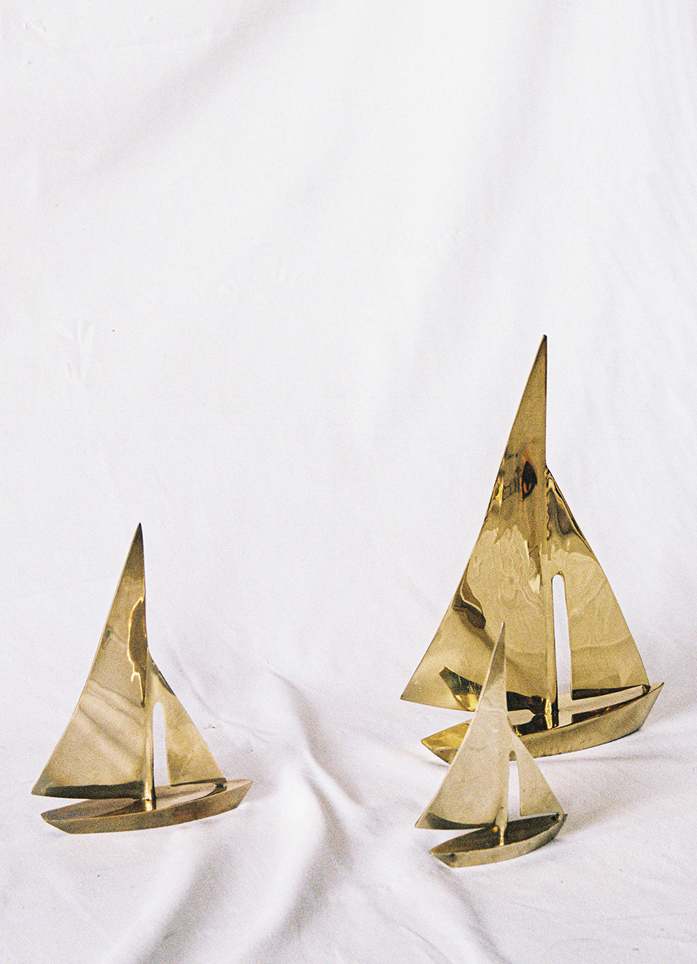 Three solid brass sailboats in graduated sizes, upright