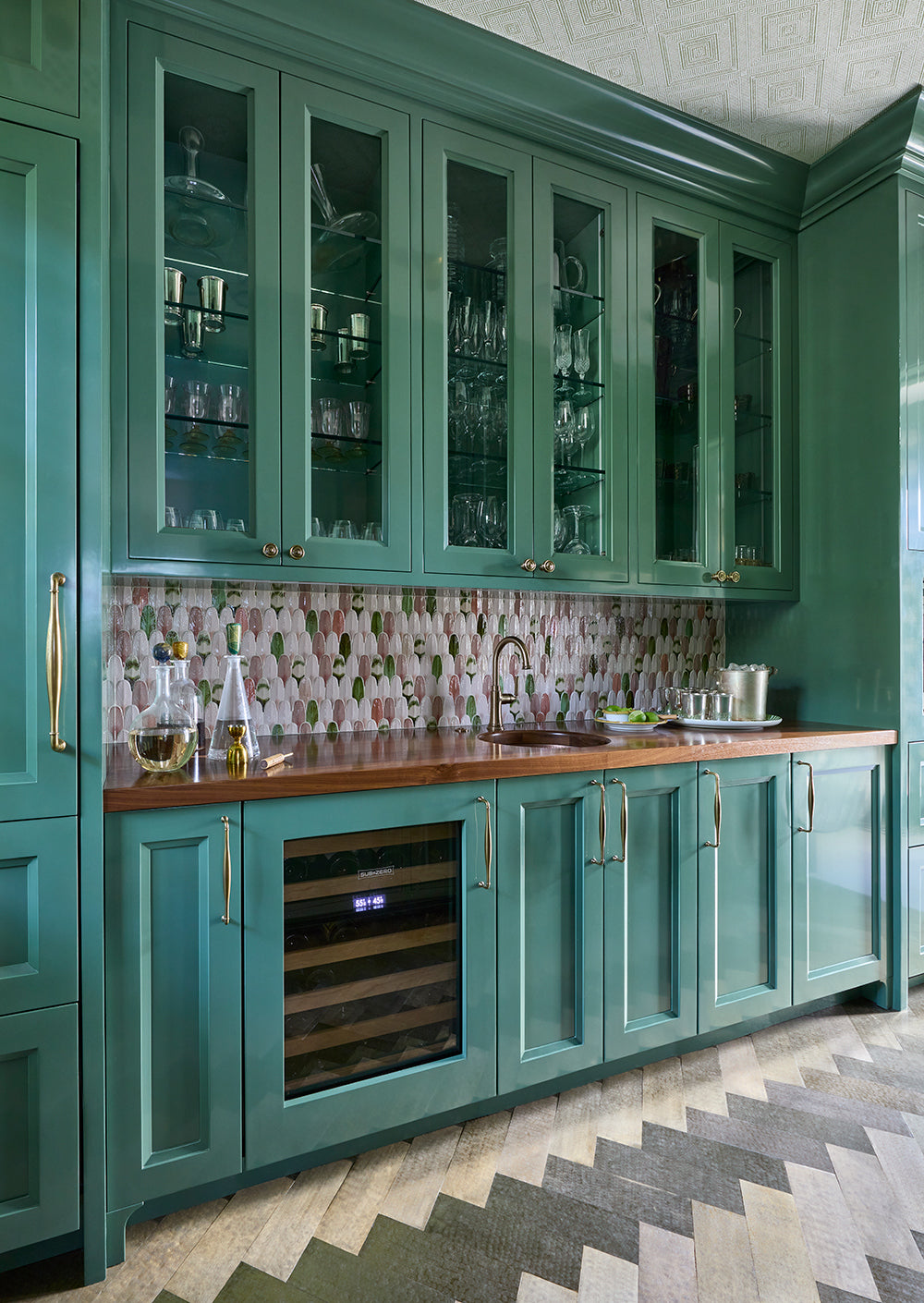 Bar with green glazed cabinets, a shell mosaic splashback and a wine fridge on a chevron floor