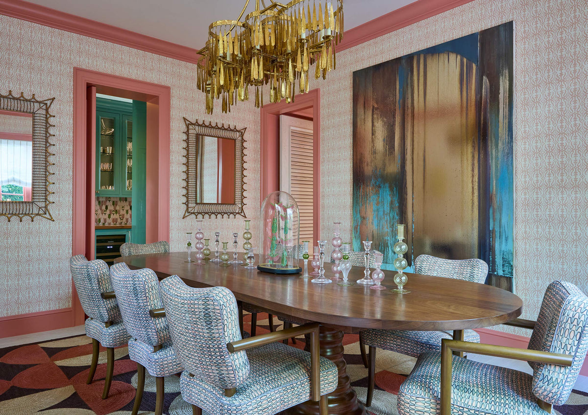 Dining room with a gilt fringe chandelier, an oval table and pale upholstered chairs against a large abstract canvas