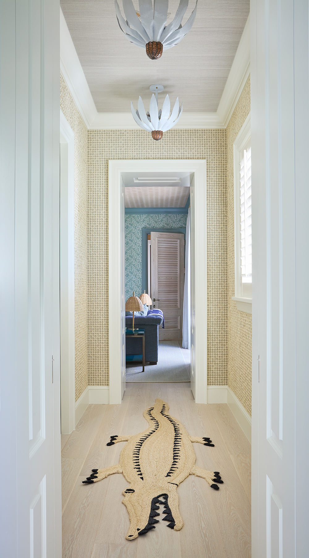Hallway with a zebra hide rug and a glass lantern, looking through to a blue room