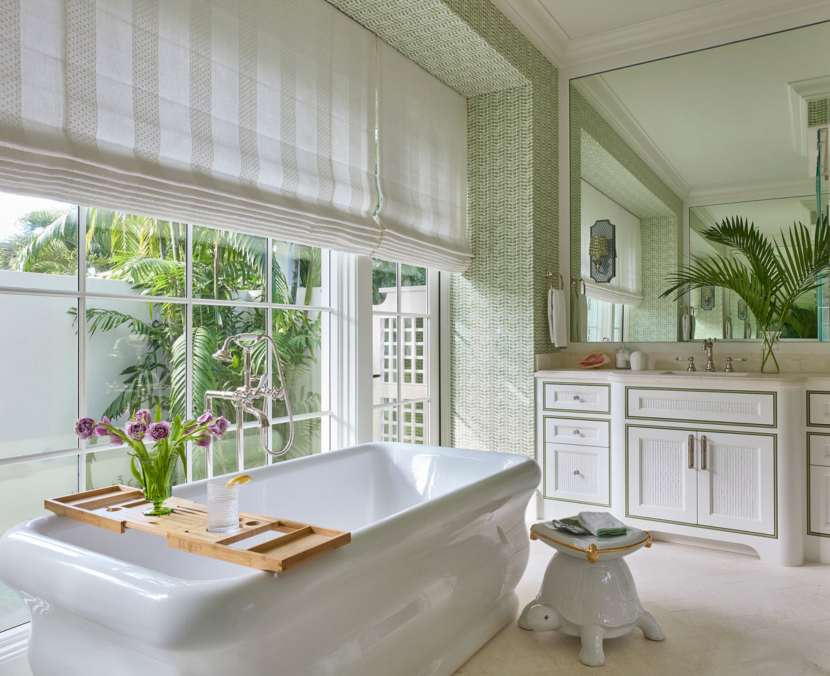 Bathroom with a freestanding tub under a woven shade, a bath tray of tulips and a white turtle stool