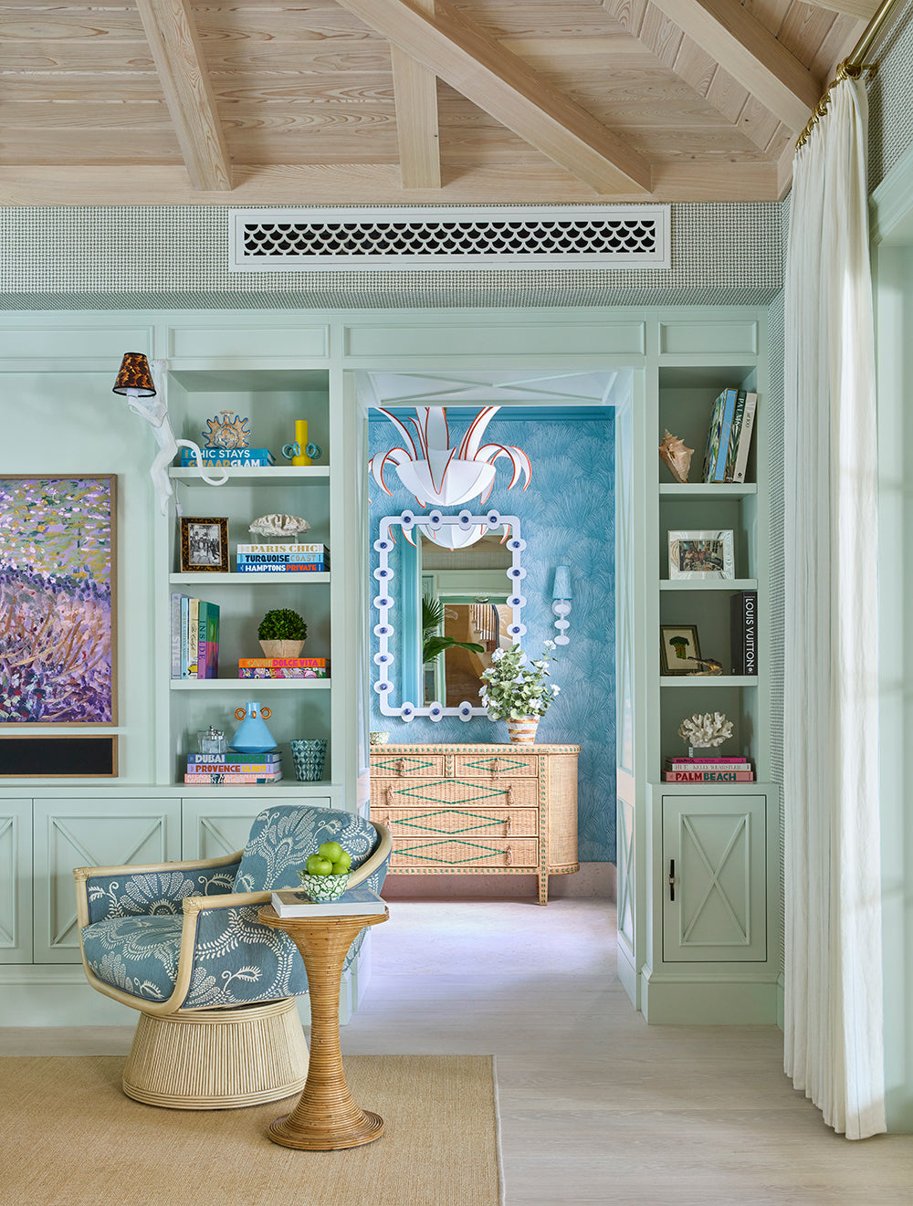 Turquoise sitting room with built in bookshelves, a white fretwork mirror, a painted cabinet and a patterned tub chair