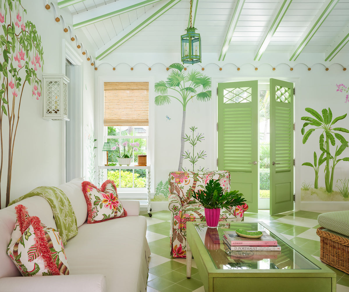 Sitting room from the doorway, painted palms, green louvred doors, a lantern pendant and white sofas with coral cushions