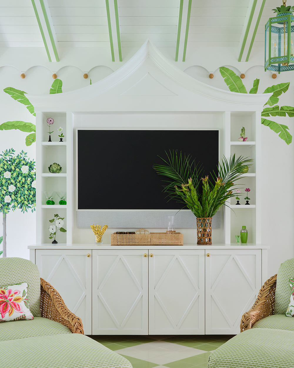 White fretwork media cabinet under a pagoda pediment, flanked by shelves of shells with a palm arrangement on top