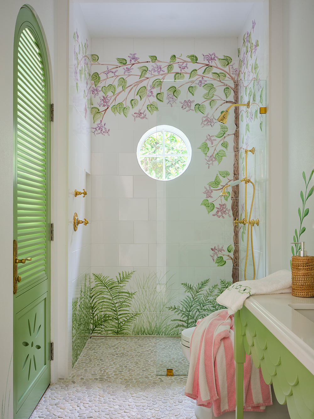 Shower room hand painted with climbing vines, a green arched louvred door, a porthole window and a pink striped towel