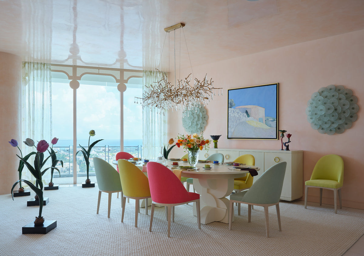 Dining room with pastel chairs around a white pedestal table, a floor to ceiling window and a tulip sculpture