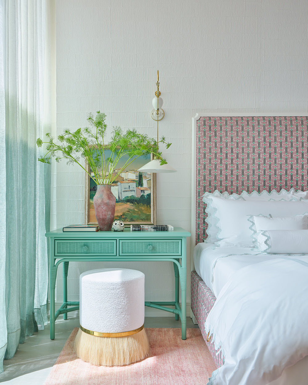 Bedside detail, a mint green console, a gold banded lamp and a small landscape painting beside a pink headboard