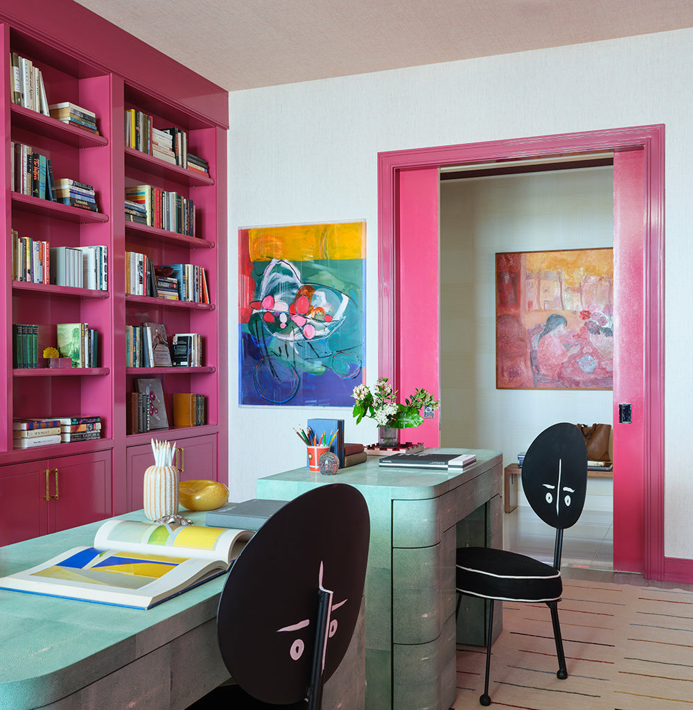 Study with magenta bookshelves and door frame, a green lacquered desk and black face backed chairs