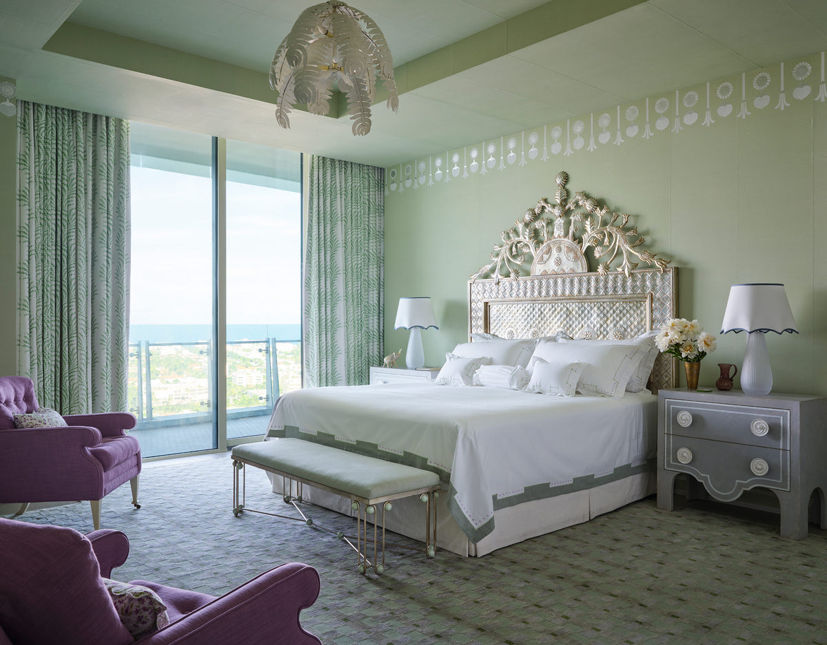 Bedroom with a carved silver headboard, purple velvet chairs, a shell pendant and a stencilled cornice